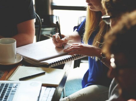 Παρέα από μαθητές γύρω από ένα τραπέζι με μία κοπέλα να κρατάει σημειώσεις