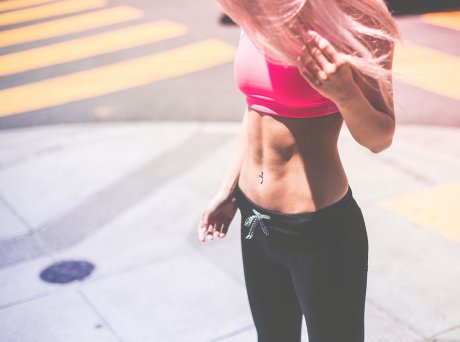 Γυναίκα σε διάβαση πεζών με ροζ μπουστάκι και μαύρο κολάν με γυμνασμένους κοιλιακούς