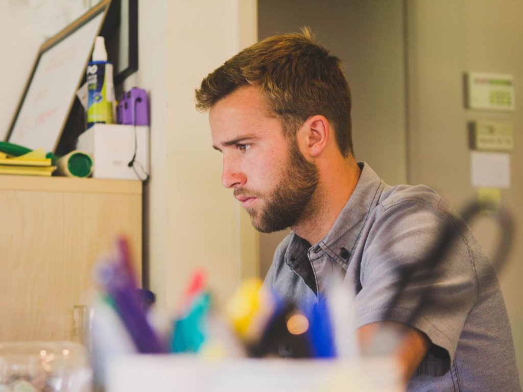 Αγόρι μπροστά στην οθόνη υπολογιστή διαβάζει στο γραφείο του