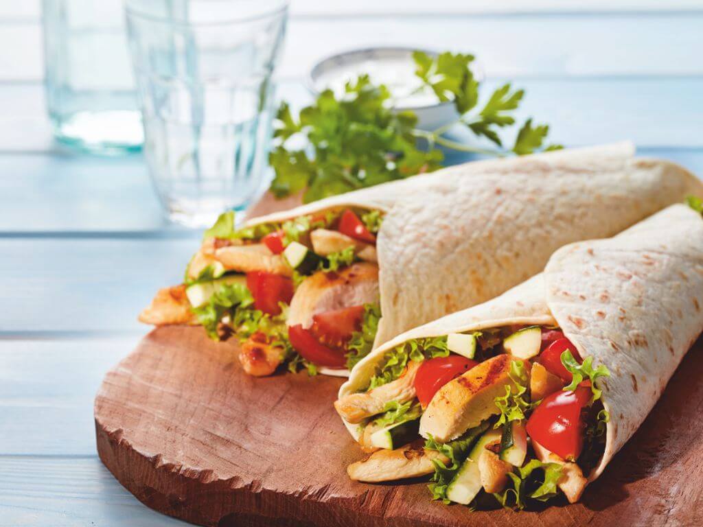 Δύο τορτίγιας πάνω σε ξύλινο πάγκο κοπής που περιέχουν κοτόπουλο και λαχανικά