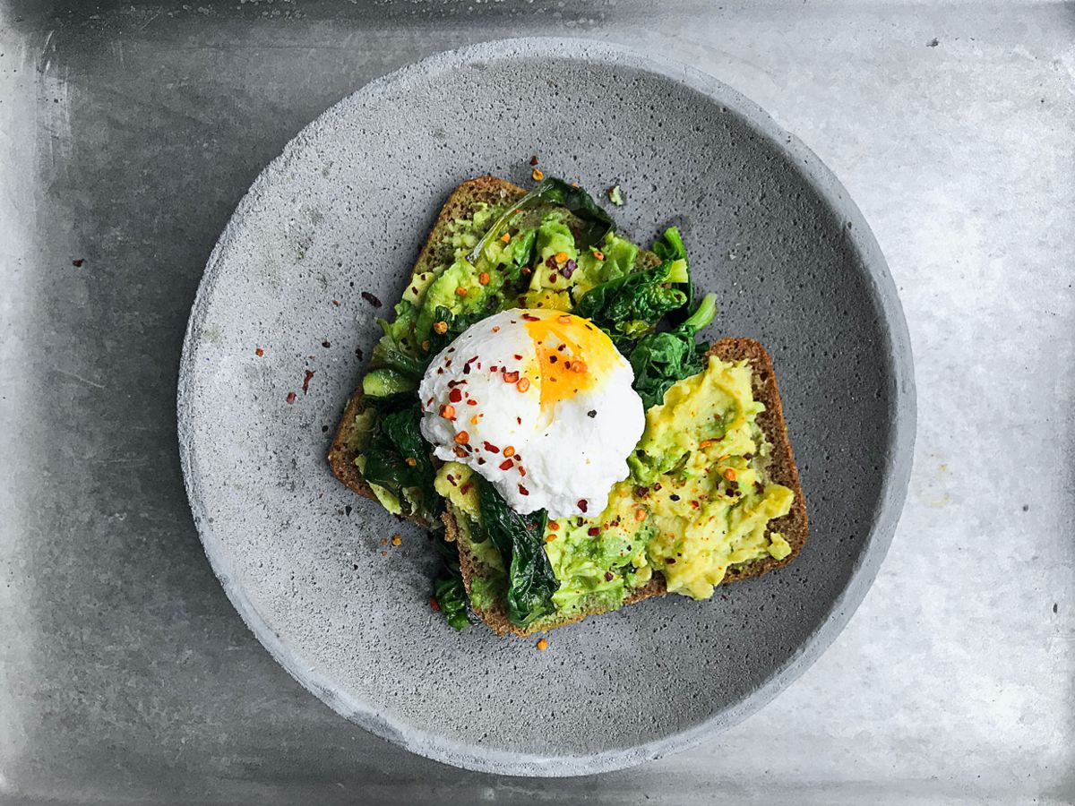 Γκρι κεραμικό πιάτο με μαύρο ψωμί αβοκάντο και Σπιρουλίνα flakes