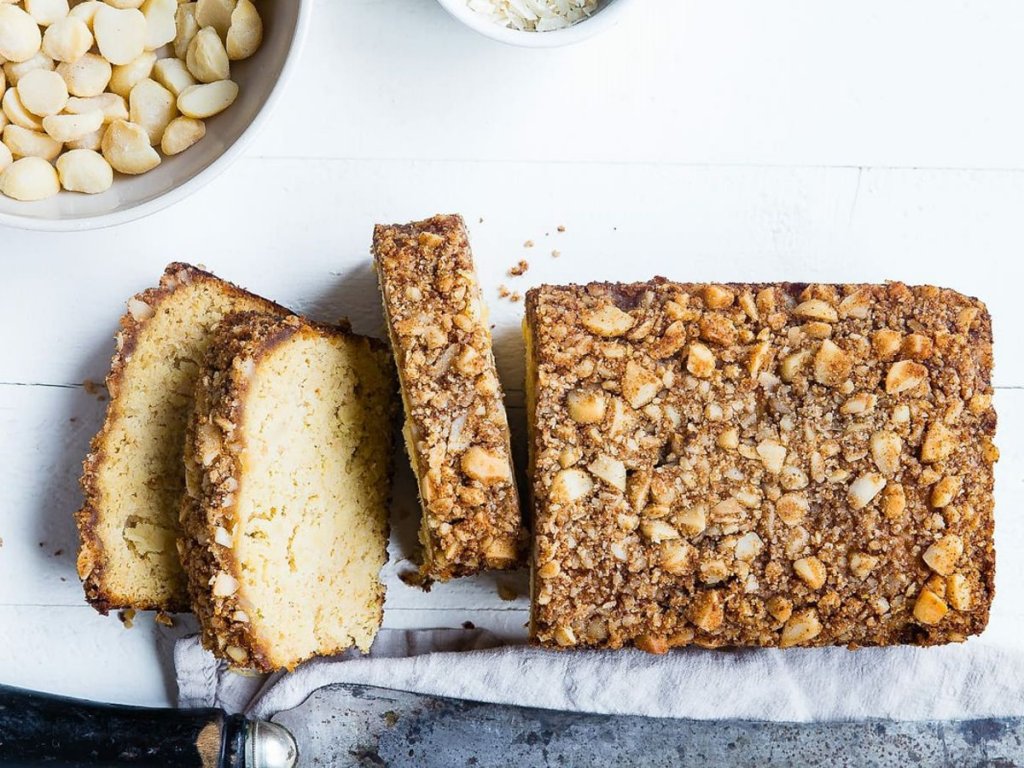 Μία φέτα κέικ δίπλα από ολόκληρο το κέικ με αμύγδαλα και άλλα υλικά