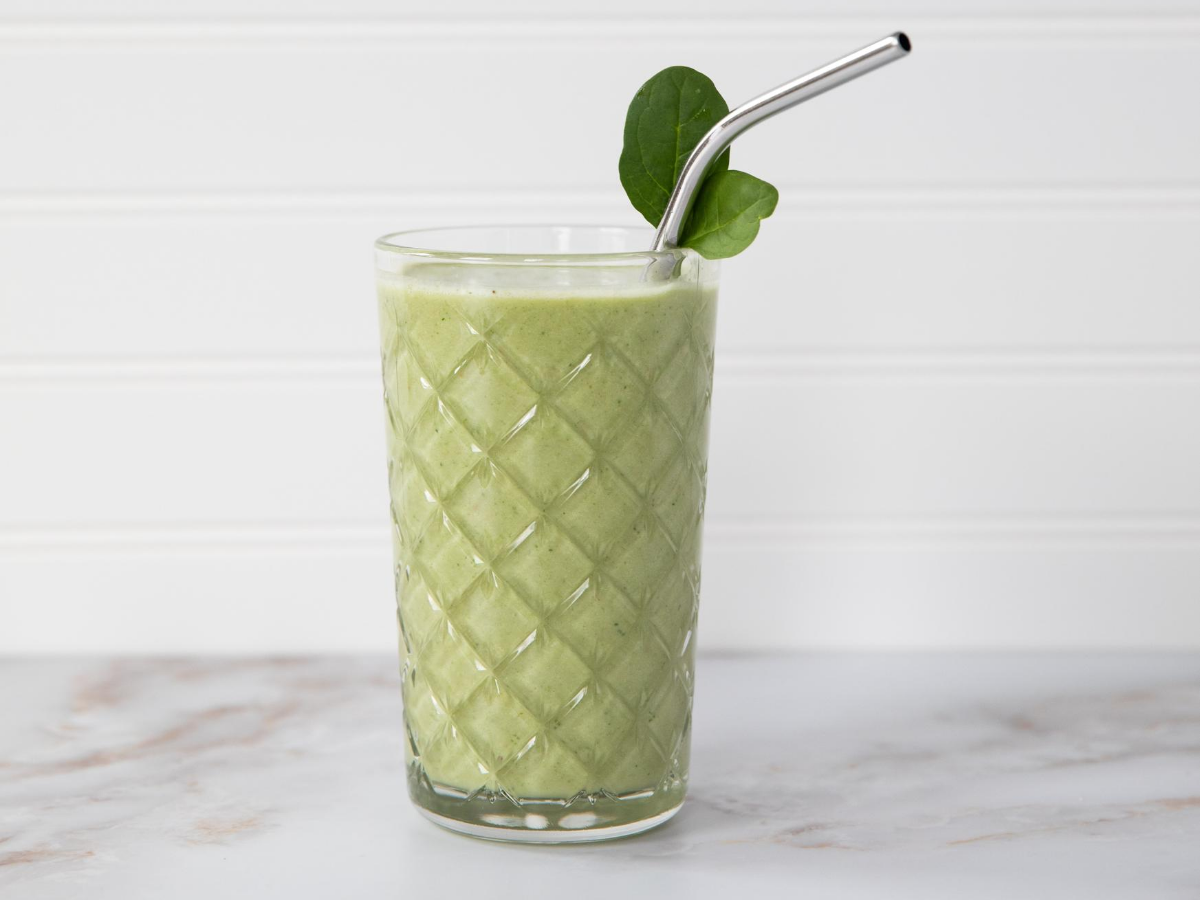 Ποτήρι με πράσινο smoothie σε λευκό φόντο