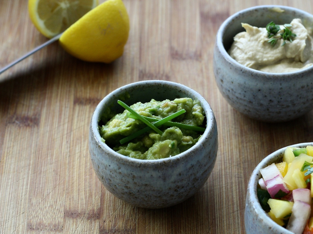 Γκρι μπολ με πράσινο χούμους σε ξύλινο πάγκο και ένα λεμόνι
