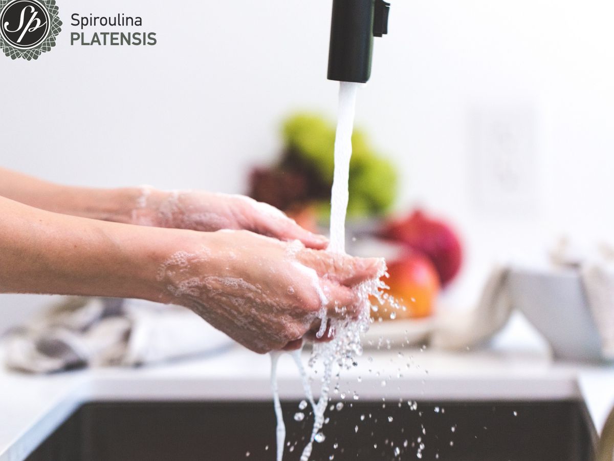 Χέρια που πλένονται κάτω από μία βρύση και στο φόντο φρούτα