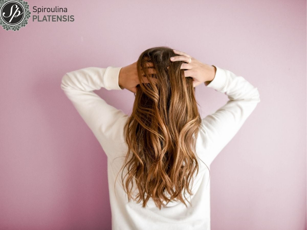 Γυναίκα με μακριά ξανθά μαλλιά σε ροζ φόντο με λευκό φούτερ