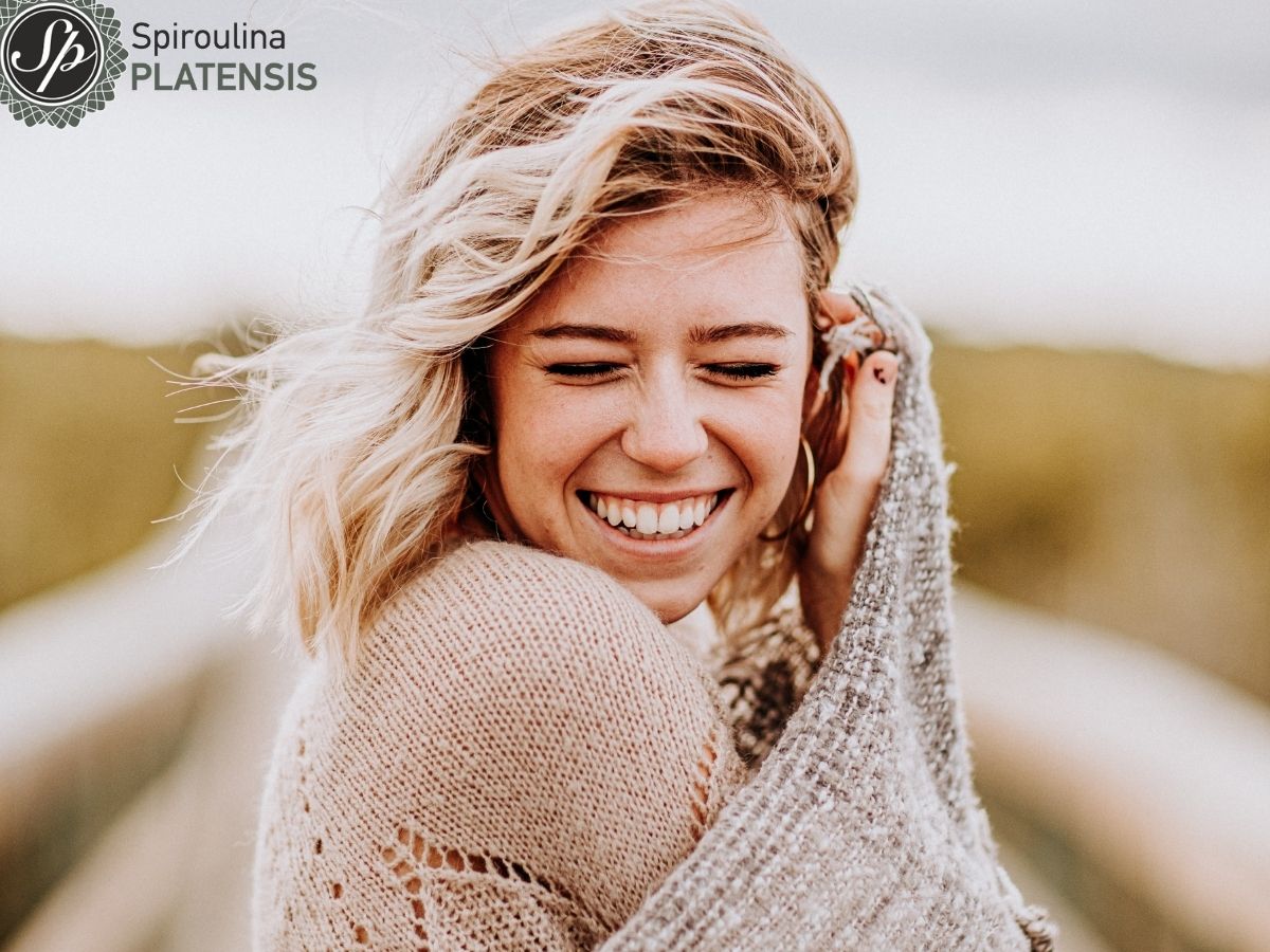 Ξιανθιά κοπέλα σε εξωτερικό χώρο με ζεστά ρούχα χαμογελάει