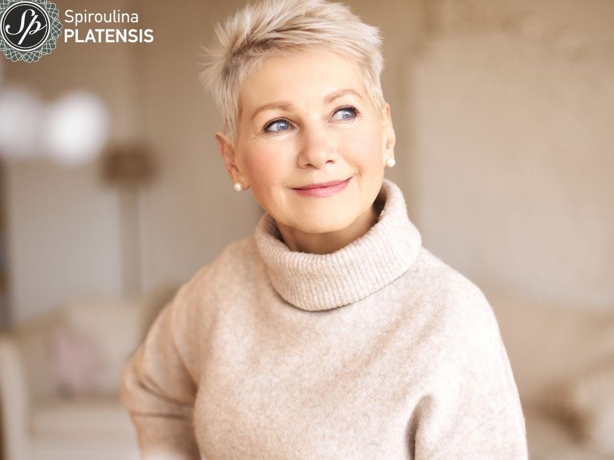 Ώριμη γυναίκα με κοντά γκρίζα μαλλιά και λαμπερό δέρμα που φοράει εκρού πουλόβερ