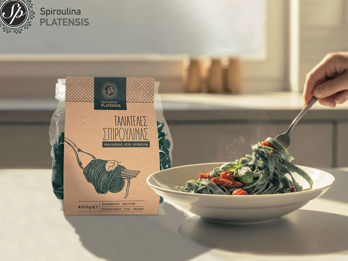 Συσκευασία ταλιατέλες Spiroulina PLATENSIS 400g δίπλα σε πιάτο με πράσινα ζυμαρικά σπιρουλίνας και ντοματίνια, σερβίρισμα με πιρούνι.