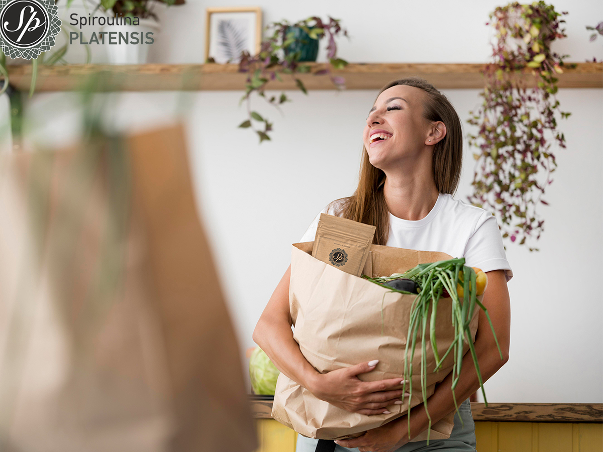 Κοπέλα που χαμογελάει και κρατάει χάρτινη σακούλα με φυσικά προϊόντα