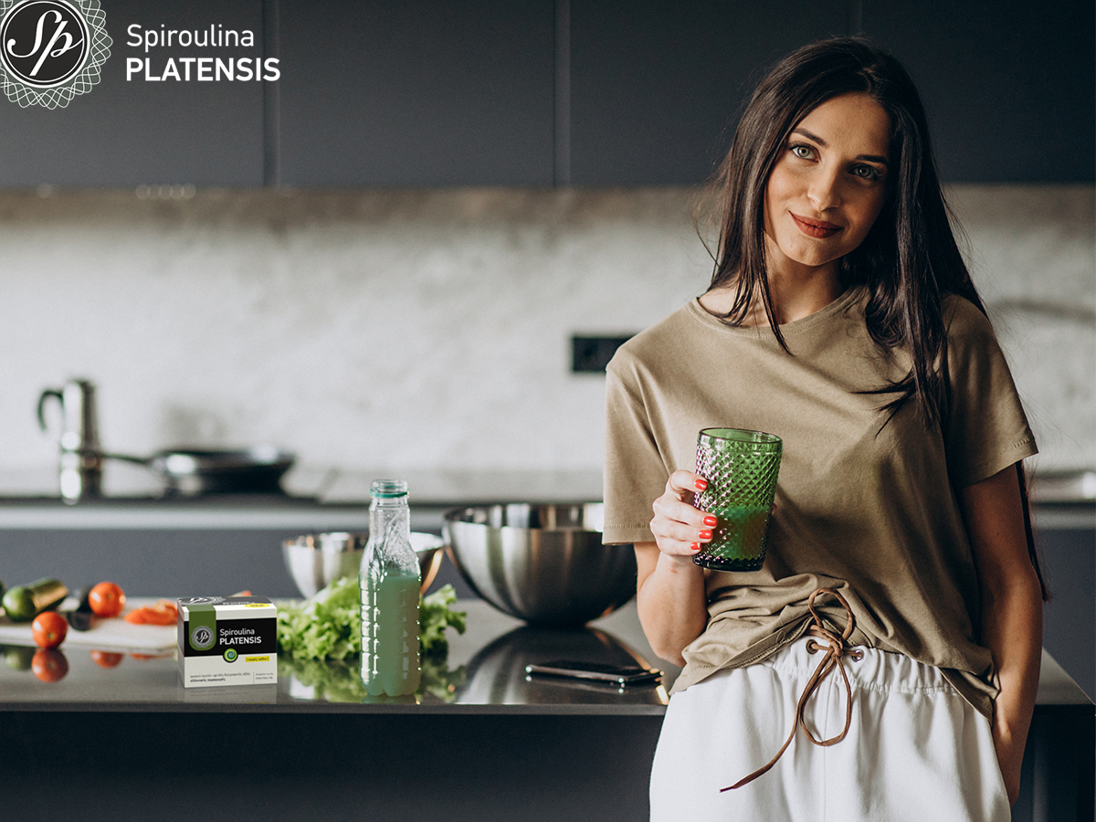 Νεαρή μελαχρινή γυναίκα που κρατάει ένα ποτήρι smoothie