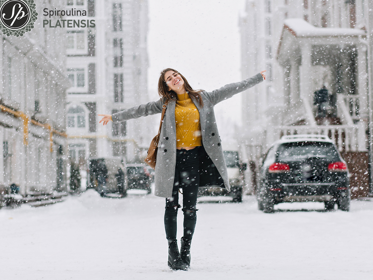 Νεαρή γυναίκα που απολαμβάνει το χιόνι στη μέση ενός δρόμου