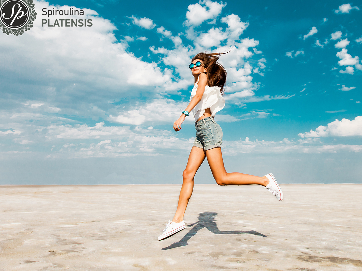 Κοπέλα με τζιν σορτσάκι σε μία παραλία που πηδάει ψηλά