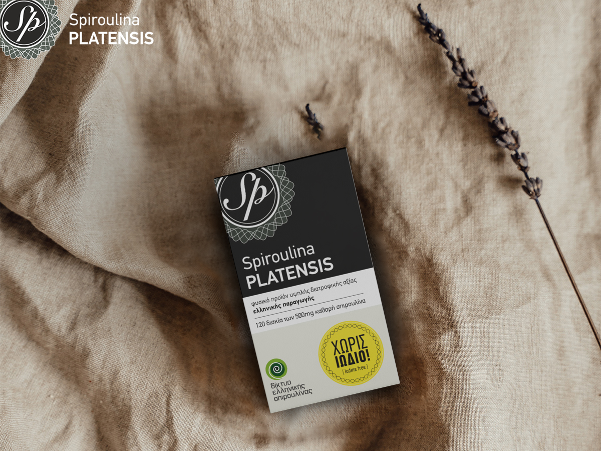 Συσκευασία Spiroulina PLATENSIS ταμπλέτες χωρίς ιώδιο πάνω σε φυσικό ύφασμα, με κλαδάκι λεβάντας στο πλάι.