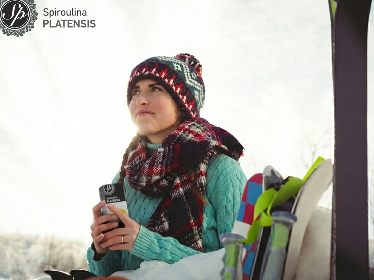 Γυναίκα σε χειμερινό τοπίο κρατά Spiroulina PLATENSIS δίπλα σε σκι, έτοιμη για βόλτα στα χιόνια.