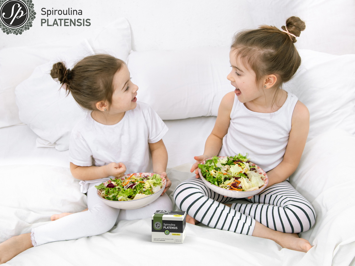 Δύο παιδιά τα οποία τρώνε υγιεινά & έχουν μπροστά τους μία συσκευασία Spiroulina PLATENSIS σκόνη