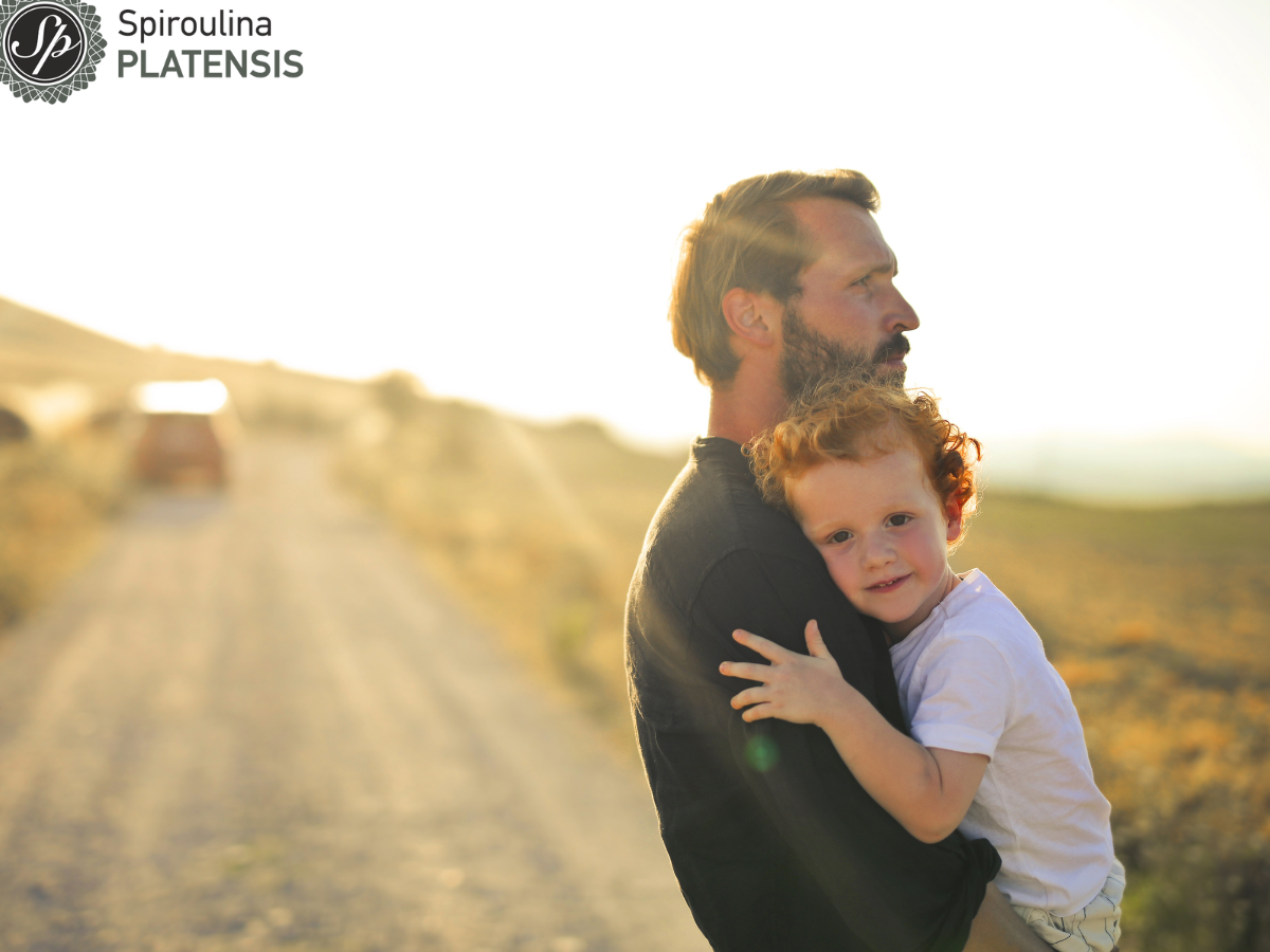 Πατέρας που έχει αγκαλιά το παιδί του σε εξωτερικό χώρο καλοκαίρι στη φύση