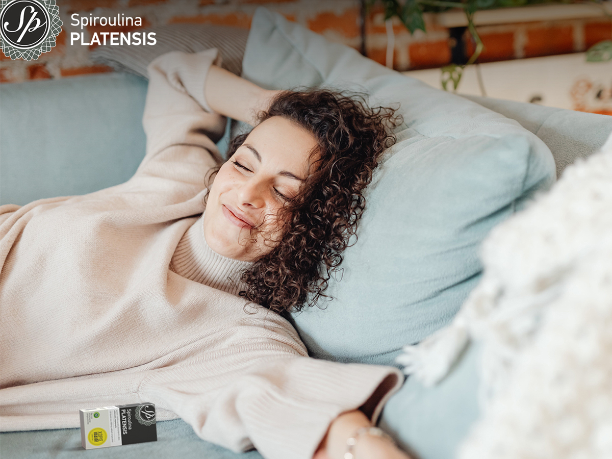 Γυναίκα χαλαρή στον καναπέ της με μία Spiroulina PLATENSIS