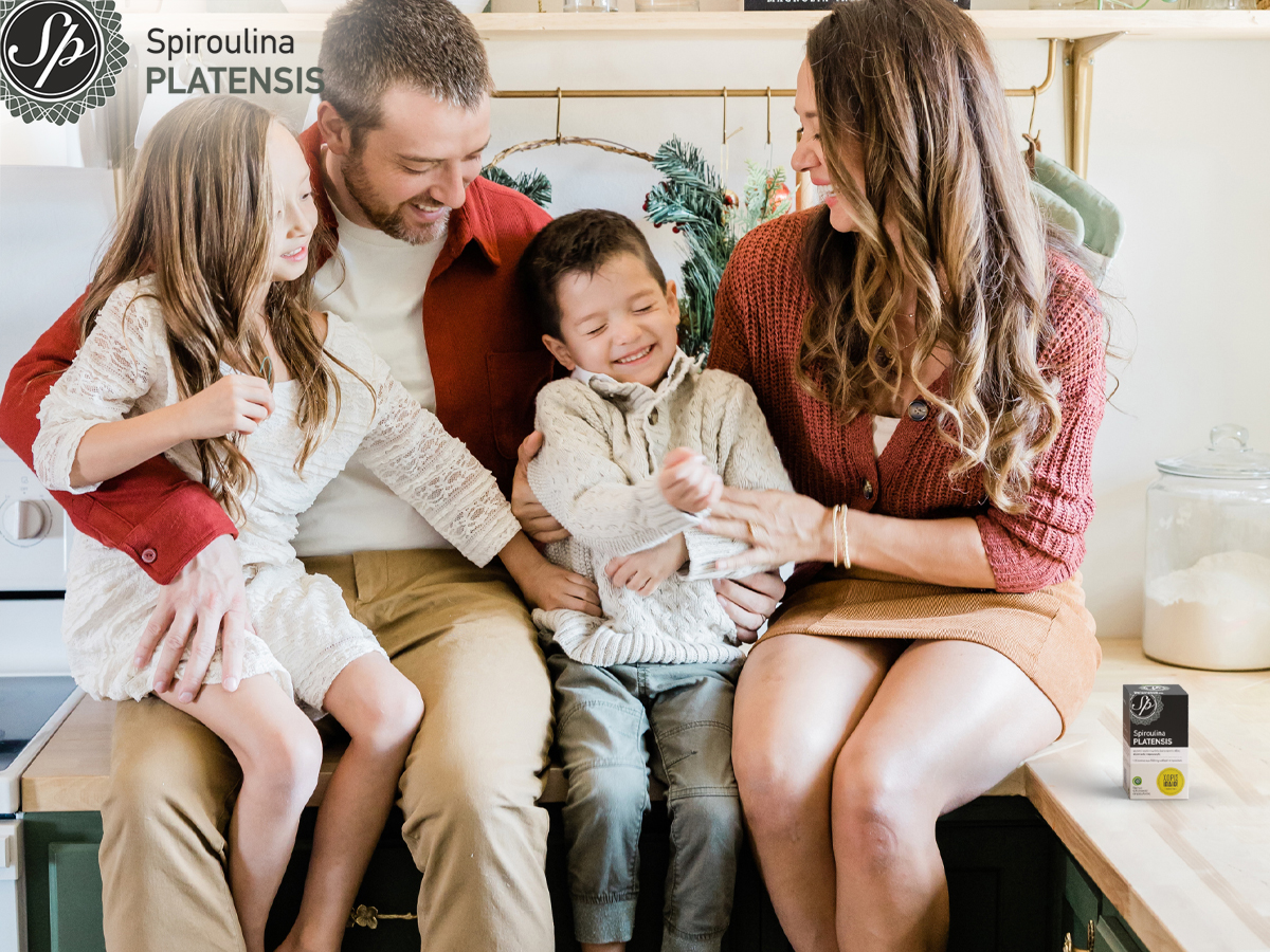 Μία οικογένεια στην κουζίνα και δίπλα μία συσκευασία Spiroulina PLATENSIS χωρίς ιώδιο