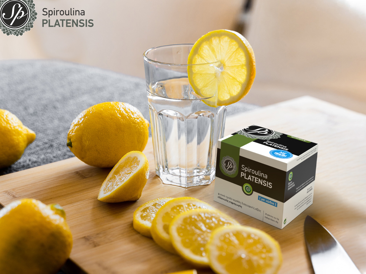 ενα ποτήρι με νερό & λεμόνια και μία συσκευασία Spiroulina PLATENSIS σε σκόνη