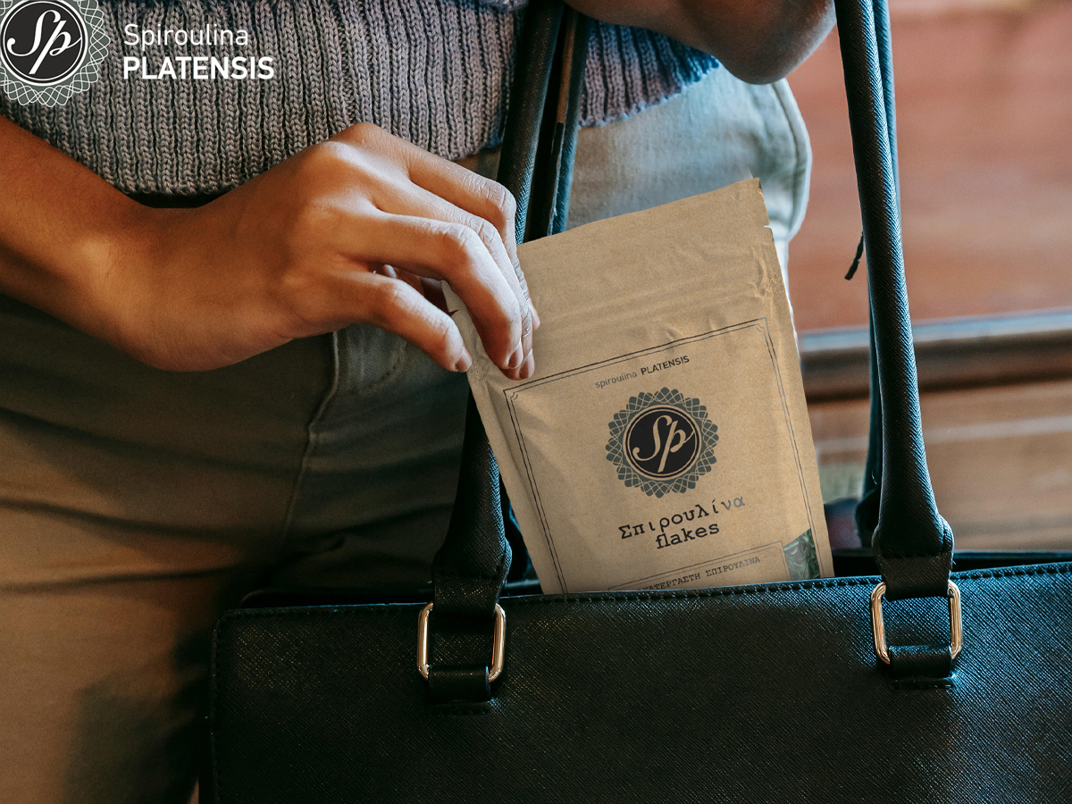Μία γυναίκα που βάζει στην τσάντα μία συσκευασία Spiroulina PLATENSIS flakes