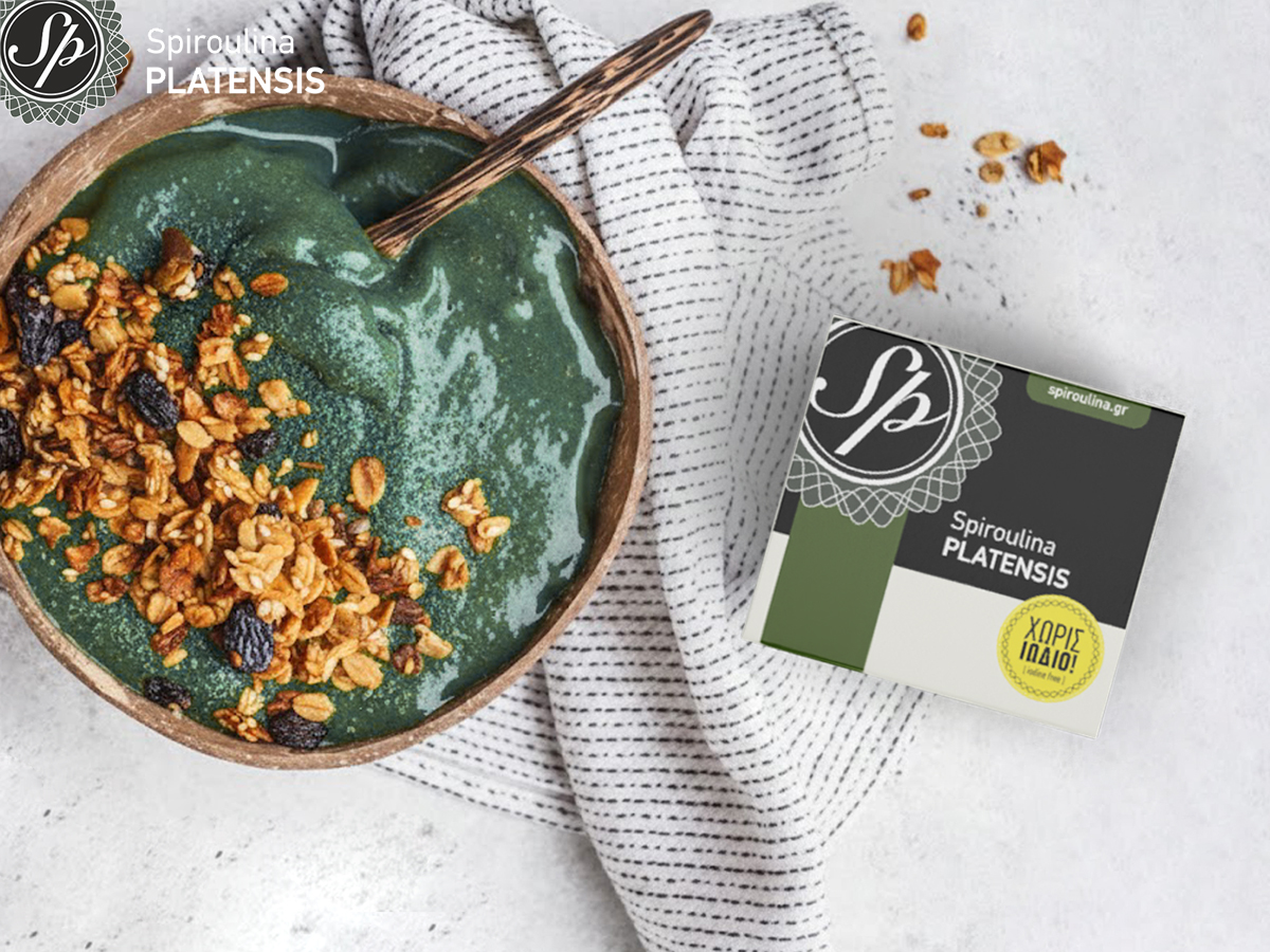 Μπολ με πράσινο smoothie (σπιρουλίνα) και γκρανόλα, δίπλα σε συσκευασία Spiroulina PLATENSIS χωρίς ιώδιο, για άρθρο «Υγιεινό πρωινό με Spiroulina PLATENSIS».